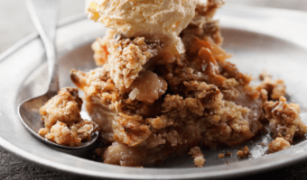 a photo of a delicious serving of apple crumble with a heavy scoop of ice cream.